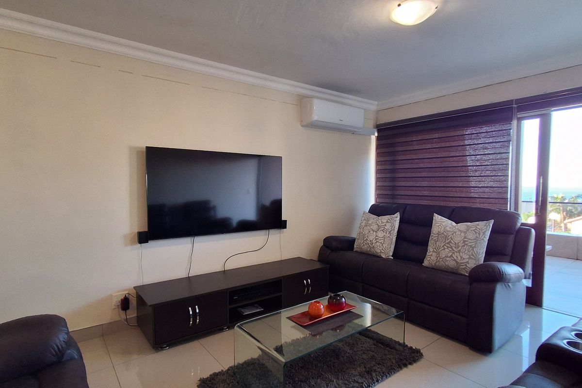 A comfortable living room featuring tiled flooring, a wall-mounted air conditioning unit, and direct access to an outdoor balcony area.