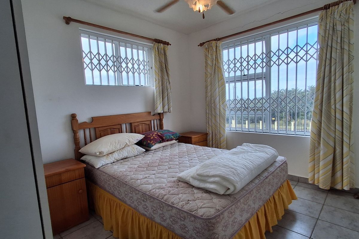 A bedroom featuring tiled flooring, ceiling fan, and security bars on the windows.