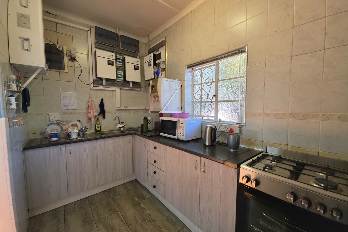 Functional kitchen featuring light wood-grain cabinetry, gas hob, electric oven, and integrated solar power infrastructure mounted on the tiled wall.