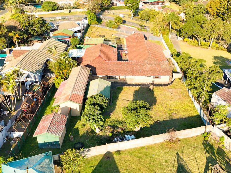 Aerial view of the property showing the main house, multiple outbuildings, and a large rear garden area with perimeter fencing.