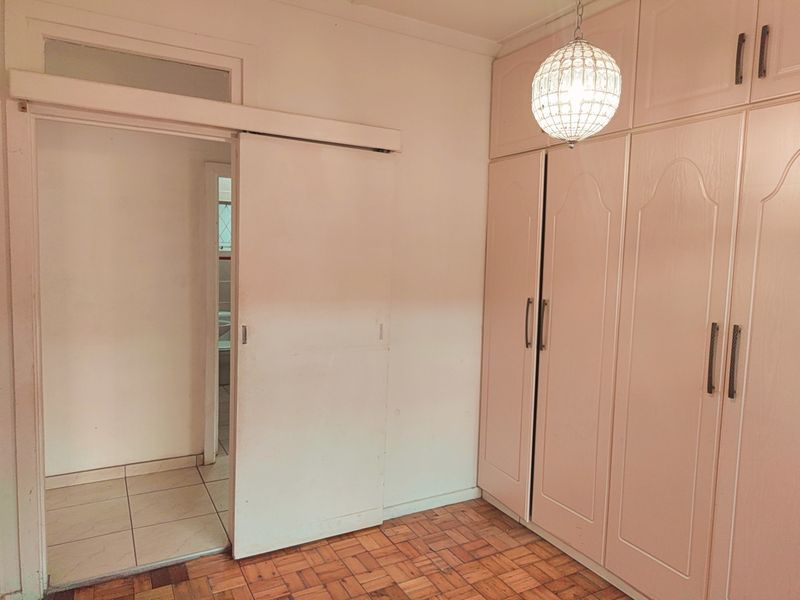 Bedroom featuring built-in floor-to-ceiling cabinetry, parquet flooring, and a sliding door leading to an adjacent tiled space.