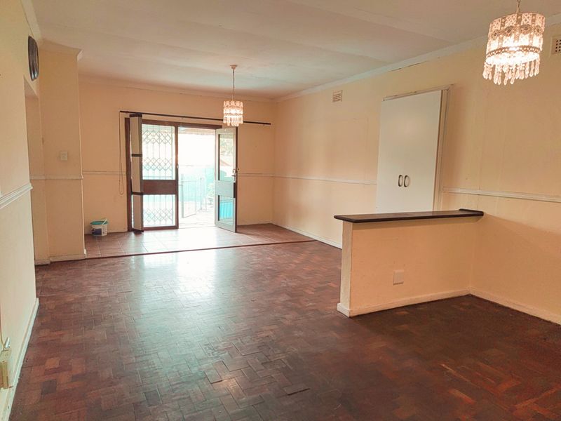 Spacious open-plan living area featuring traditional parquet flooring, built-in cabinetry, and direct access to an outdoor patio through a security gate.