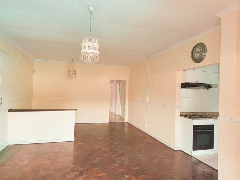 Open plan living area featuring parquet flooring, a breakfast counter, and a compact kitchen equipped with a built-in oven and extractor fan.
