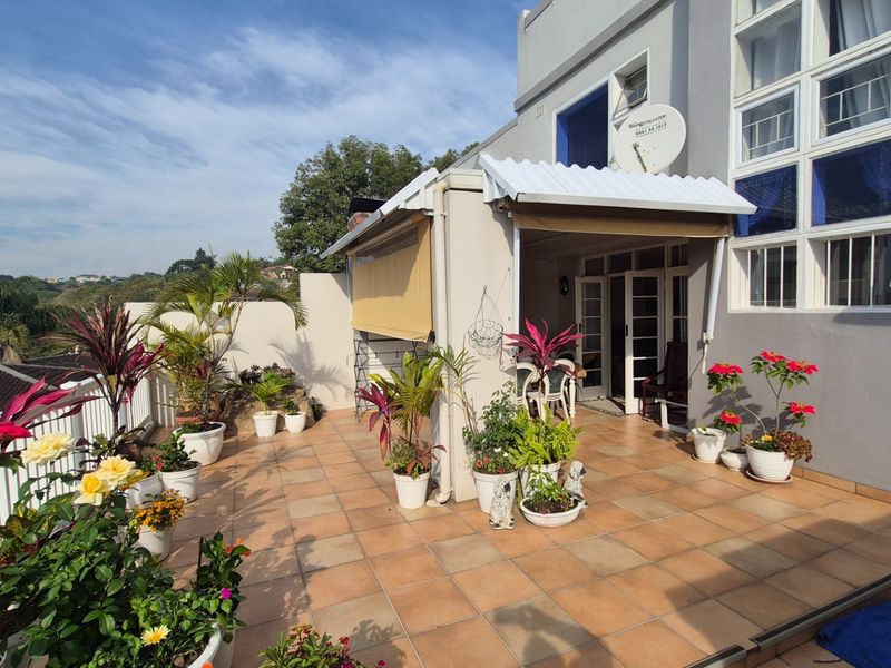 A spacious tiled patio area featuring a covered section, providing an ideal outdoor space for relaxation and entertaining.