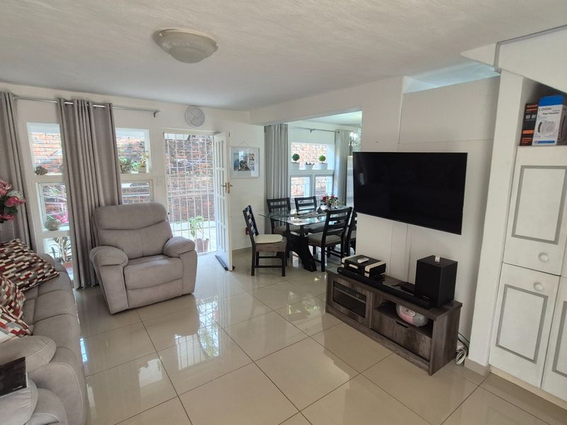 Open plan living and dining area featuring polished floor tiles, built-in storage cabinetry, and direct access to an outdoor space.