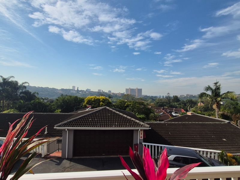Elevated view overlooking the surrounding residential neighbourhood and distant cityscape, featuring tiled rooflines and mature greenery.