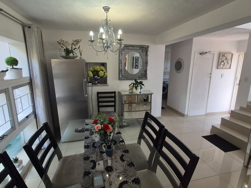 Open plan dining area featuring tiled flooring, a decorative chandelier, and a staircase leading to the upper level.