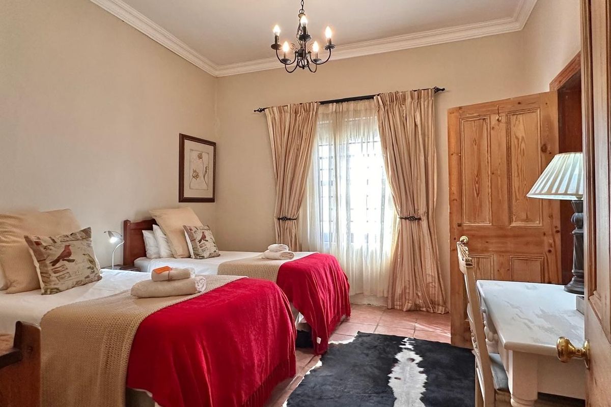 A well-maintained bedroom featuring terracotta floor tiles, crown molding, and a classic wooden door, providing a comfortable and inviting space.