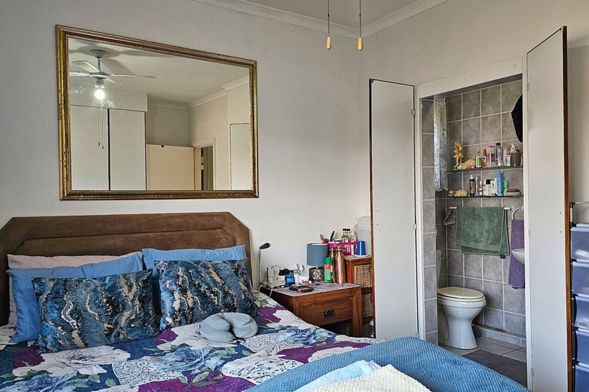 A bedroom featuring an en-suite bathroom with tiled walls and a built-in toilet, providing convenient private facilities.