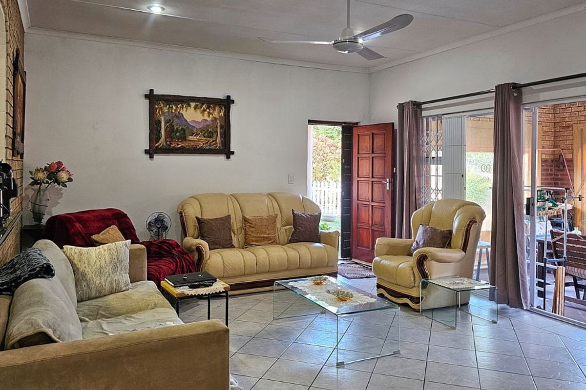 A spacious living room featuring tiled flooring, a ceiling fan, and large sliding glass doors providing direct access to an outdoor patio area.