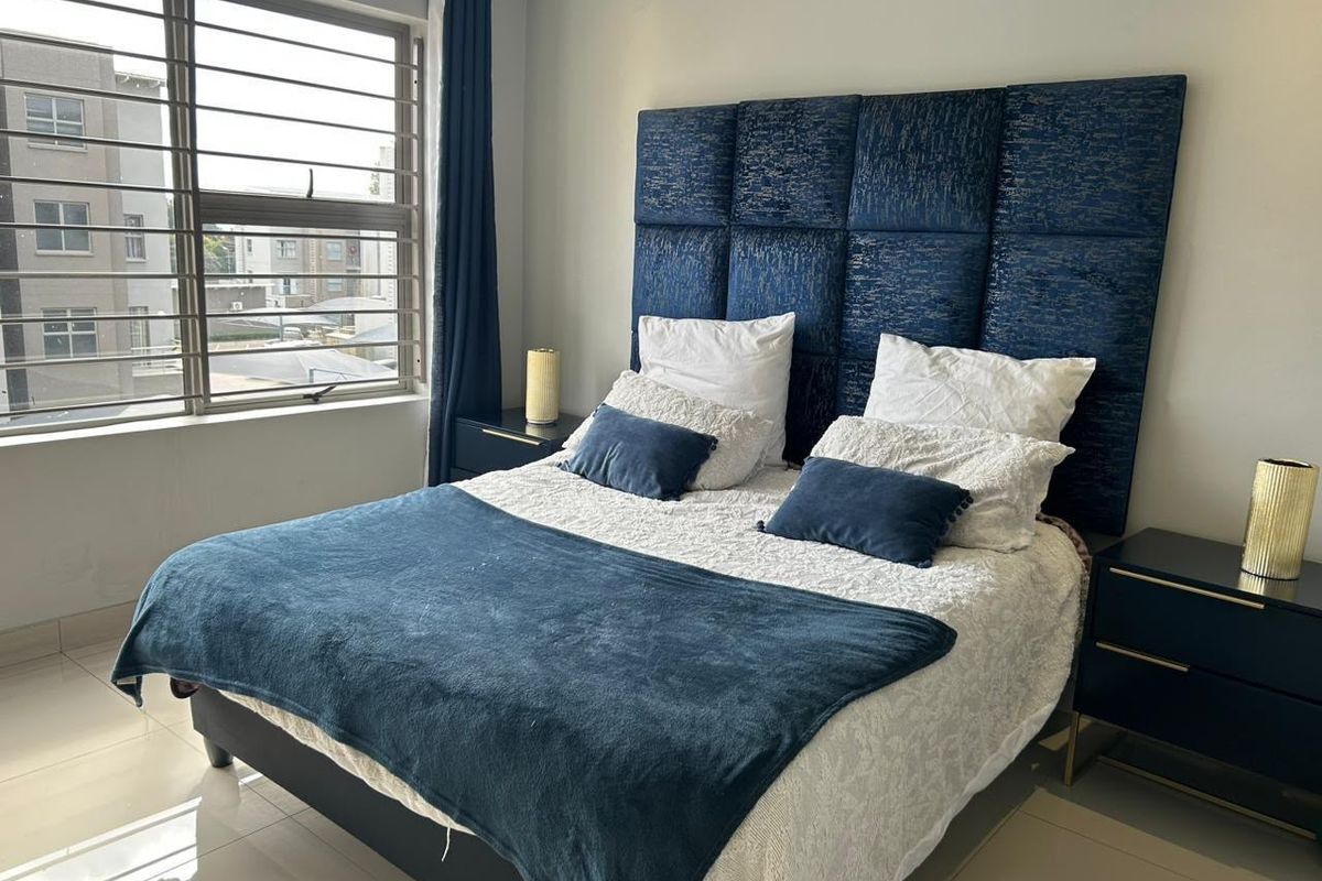 A well-maintained bedroom featuring large windows with security bars, tiled flooring, and neutral wall finishes.