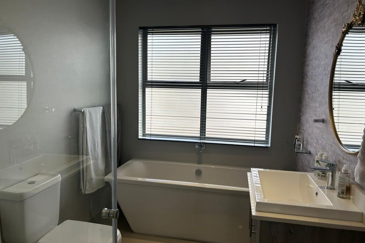 Modern bathroom featuring a freestanding bathtub, glass-enclosed shower, vanity with basin, and tiled flooring.