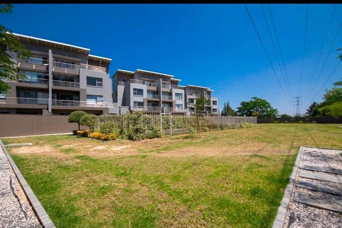 A view of the apartment complex exterior featuring modern multi-story architecture with balconies and a shared garden area.