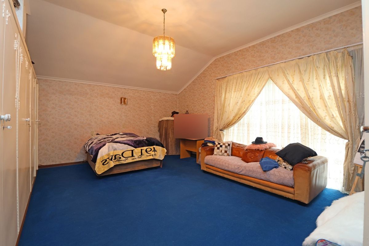 Spacious bedroom featuring built-in wardrobes, vaulted ceilings, and large windows with natural light, offering a blank canvas for modernization.