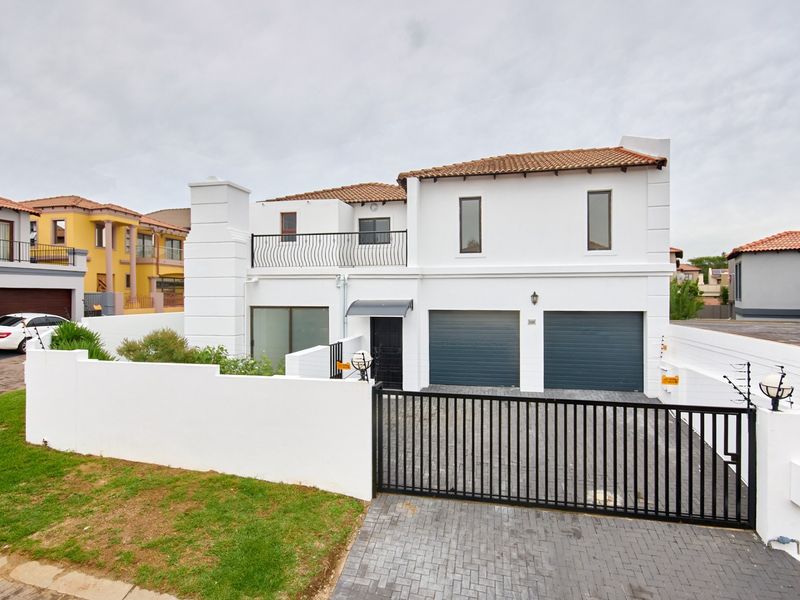 Front elevation of a two-story residential property featuring a double garage, paved driveway, secure perimeter wall with electric fencing, and an upper-level balcony.