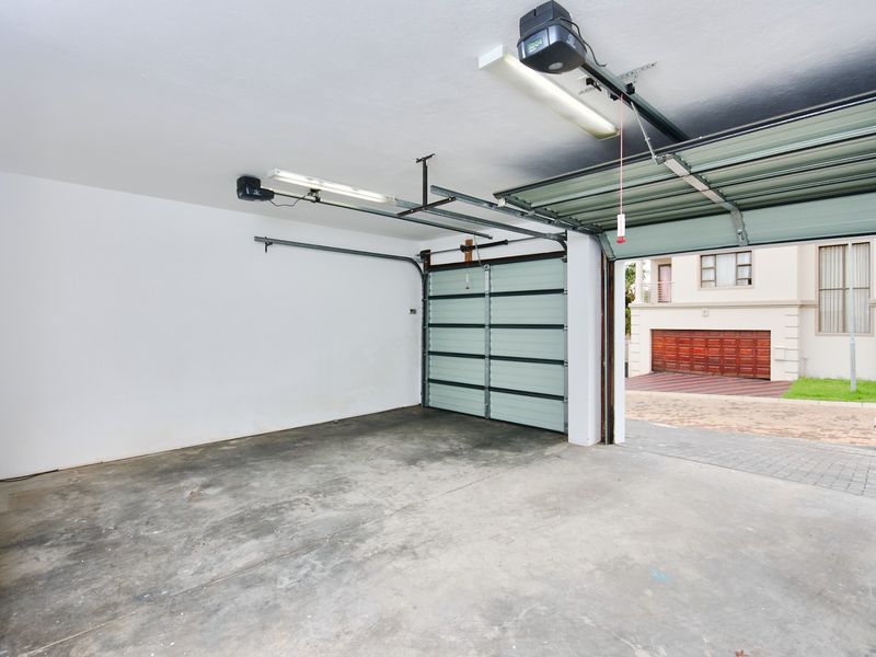 A spacious, clean double garage featuring automated doors, fluorescent lighting, and a convenient utility sink, providing ample storage and parking space.