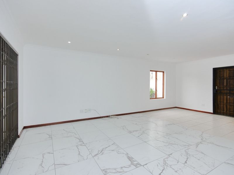 Spacious open-plan living area featuring modern marble-look floor tiles, recessed lighting, and secure access points, providing a clean and versatile blank canvas.