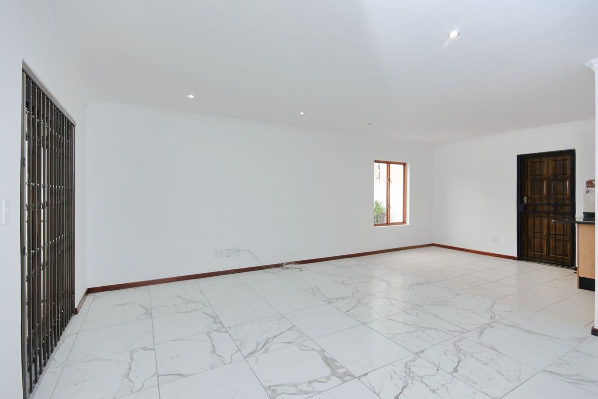 A spacious, empty living area featuring modern marble-look floor tiles, recessed lighting, and secure access points, providing a clean canvas for interior design.