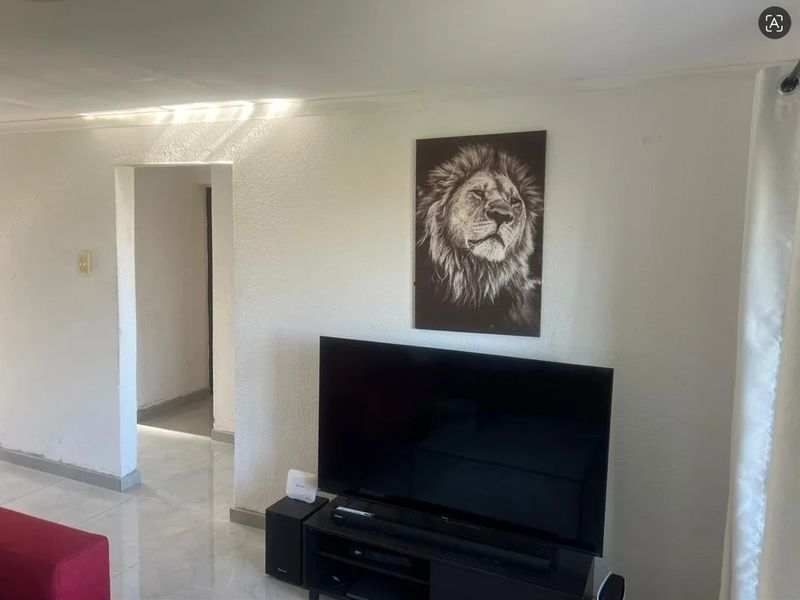 A living room area featuring tiled flooring and a doorway leading to an adjacent hallway.