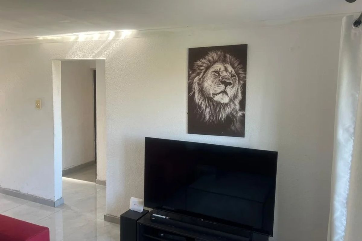 A living room area featuring tiled flooring and a doorway leading to an adjacent hallway.