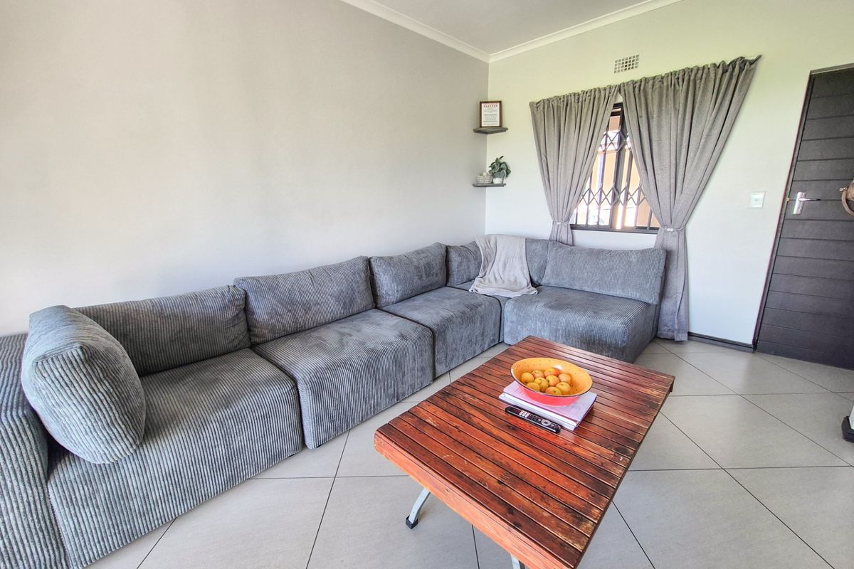 A bright living room featuring neutral floor tiles, a security gate on the window, and a solid entrance door.