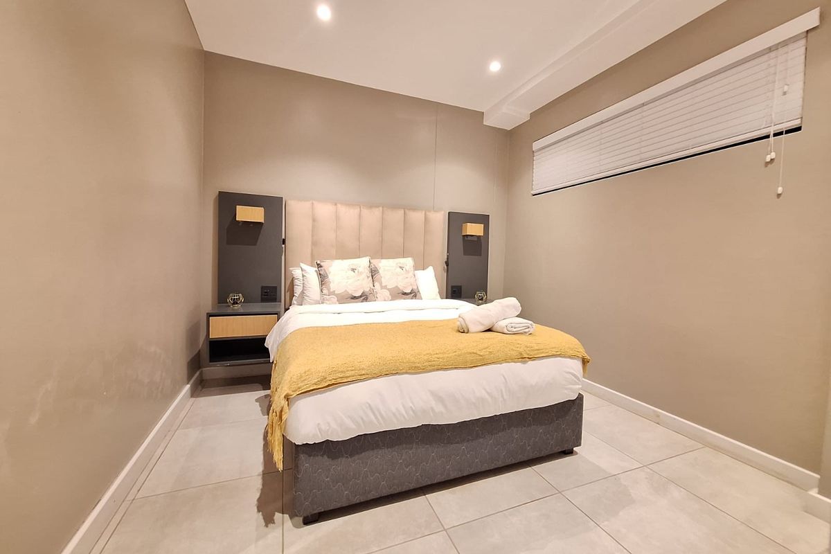 A bedroom featuring tiled flooring, recessed ceiling lighting, and built-in bedside cabinetry with integrated headboard panels.
