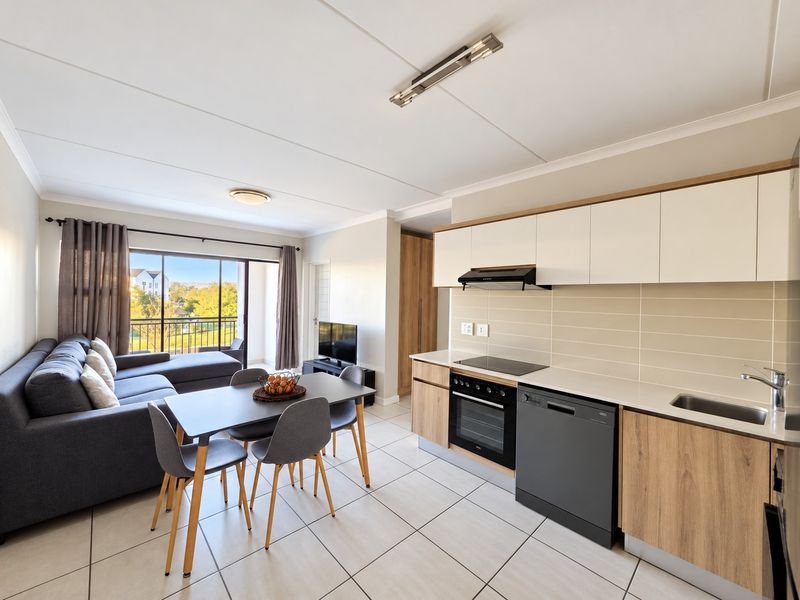 Modern open-plan living area featuring a well-appointed kitchen with sleek cabinetry, integrated appliances, and seamless flow to a private balcony.