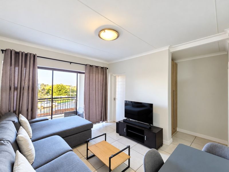 A bright living room featuring tiled flooring, a built-in cupboard, and a sliding glass door leading to a balcony.