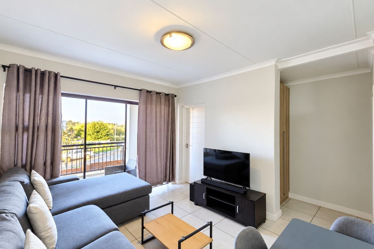A bright living room featuring tiled flooring, a built-in cupboard, and a sliding glass door leading to a balcony.