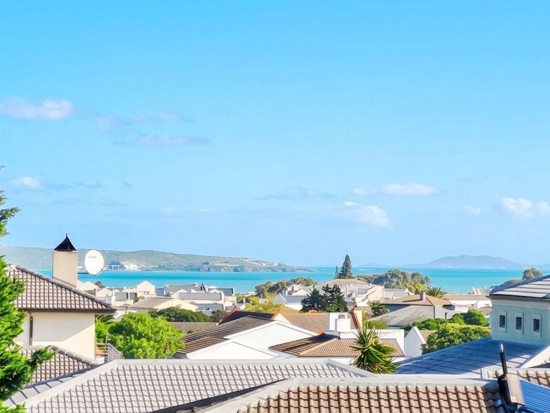 Elevated coastal view overlooking the surrounding residential neighborhood and the distant bay, showcasing the property's scenic outlook.