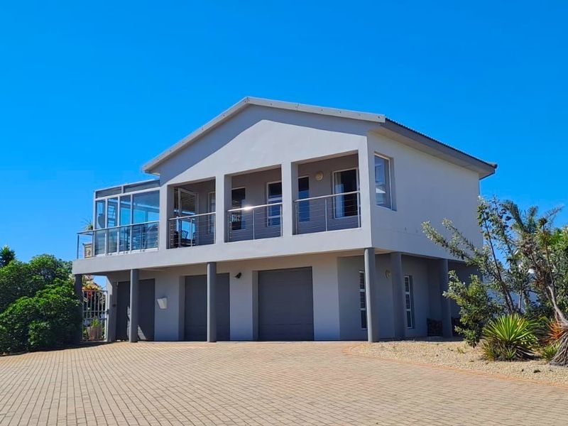 A modern two-story house featuring a paved driveway, double garage, and an elevated balcony with steel railings.