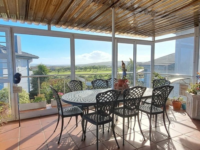 Enclosed patio area featuring tiled flooring, corrugated roofing, and expansive glass sliding doors offering scenic outdoor views.
