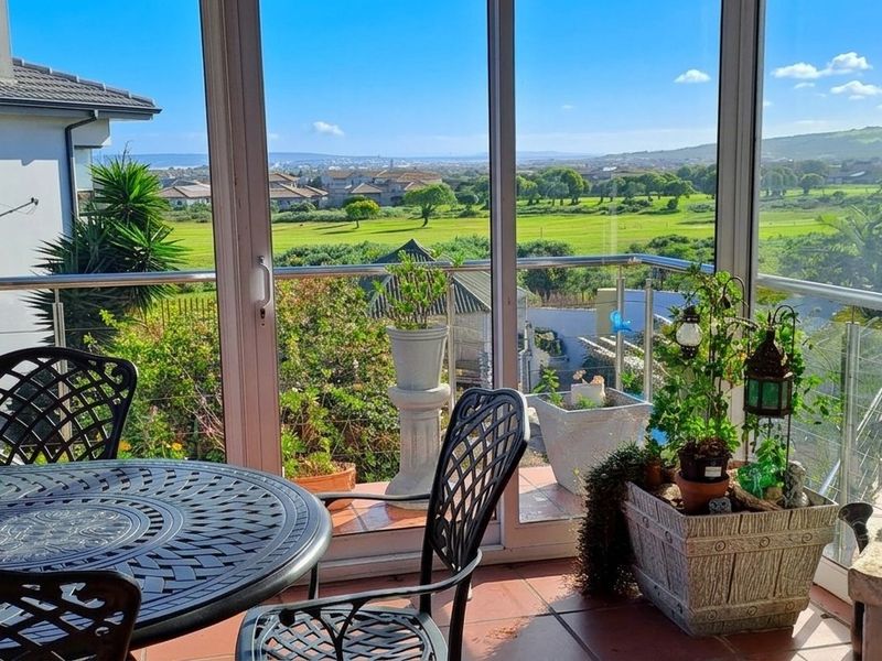 Enclosed balcony featuring large glass sliding doors, stainless steel balustrades, and tiled flooring, offering expansive views over the surrounding landscape.