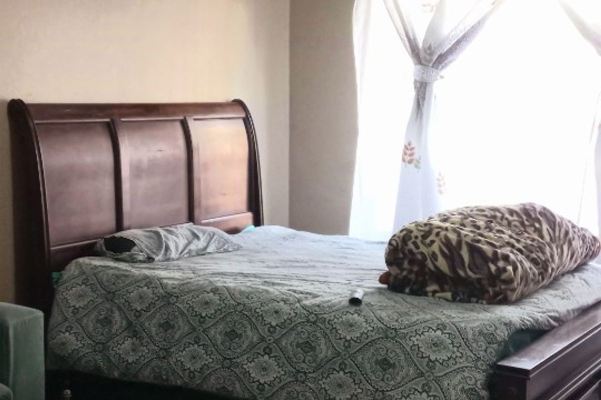A bedroom featuring tiled flooring and a window with curtain rod installation.