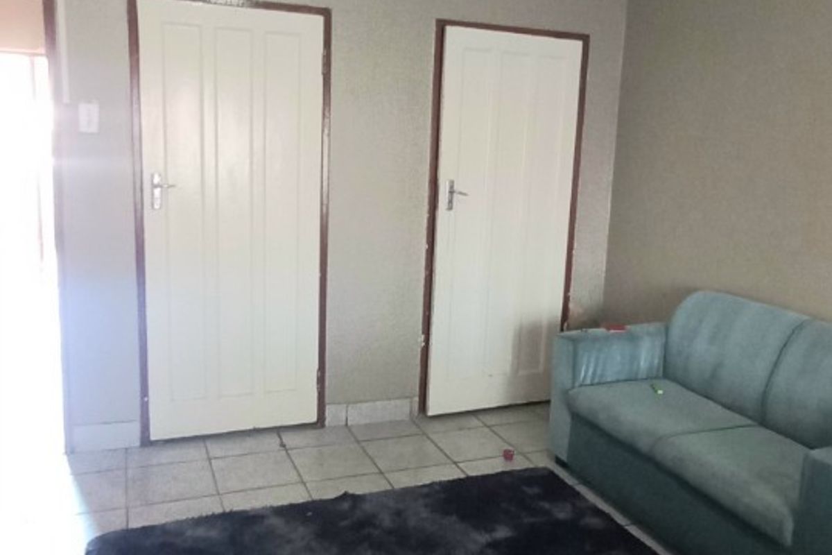 A living room area featuring tiled flooring and two interior doors, providing access to adjacent rooms within the home.