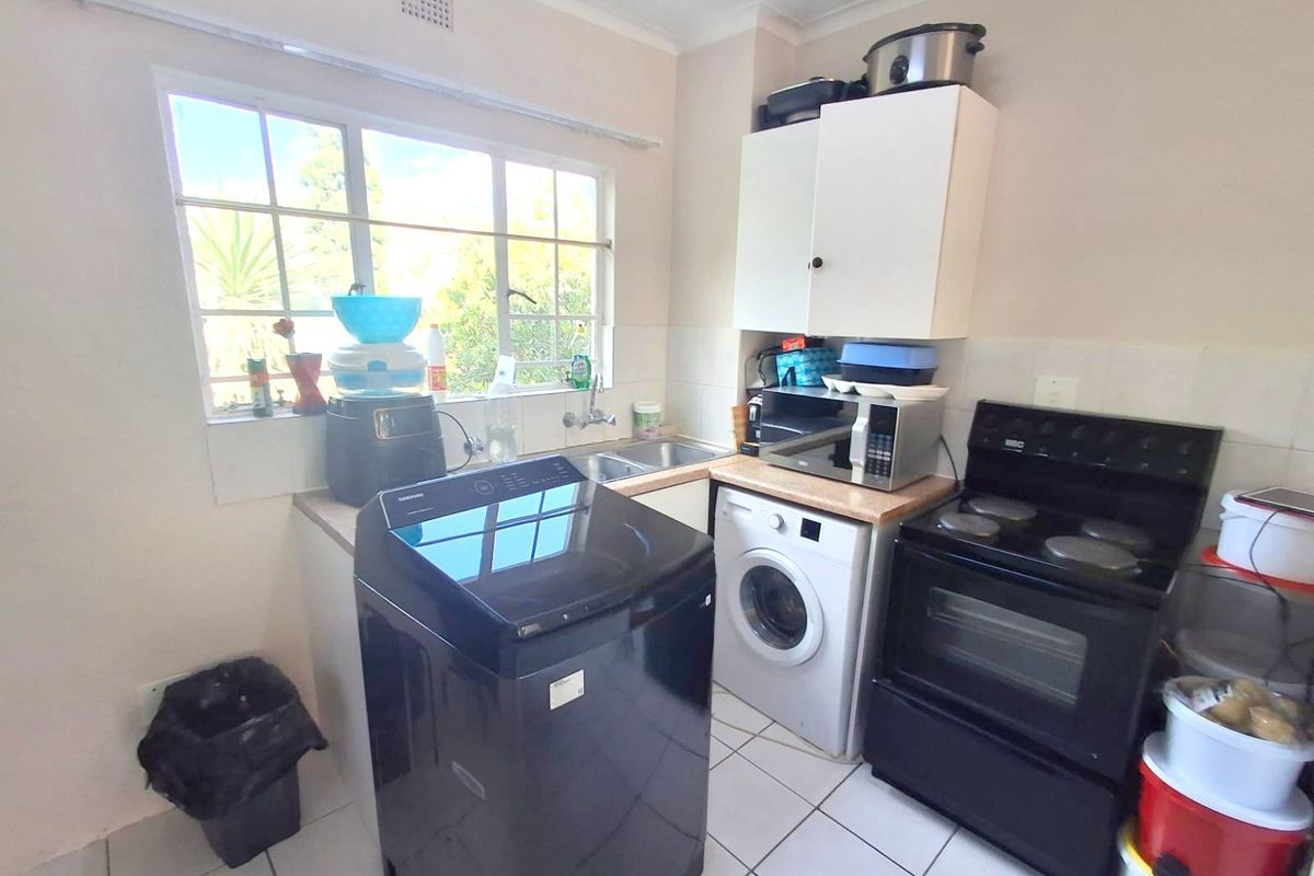 Compact kitchen featuring tiled flooring, built-in cabinetry, a double sink, and space for a freestanding stove and laundry appliances.