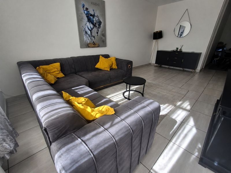 A bright and modern living room featuring neutral tiled flooring and clean white walls, offering a comfortable and well-maintained living space.