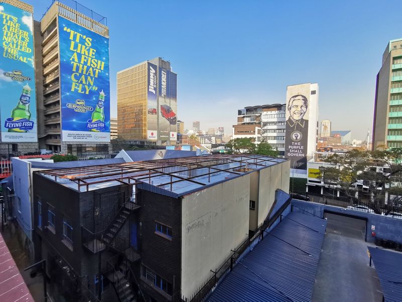 Aerial view of a commercial building rooftop featuring a metal frame structure and external fire escape, situated within a dense urban city environment.