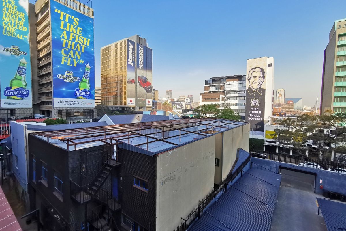Aerial view of a commercial building rooftop featuring a metal frame structure and external fire escape, situated within a dense urban city environment.