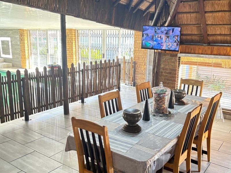 Covered outdoor patio area featuring a thatched roof, tiled flooring, and direct access to an adjacent swimming pool.