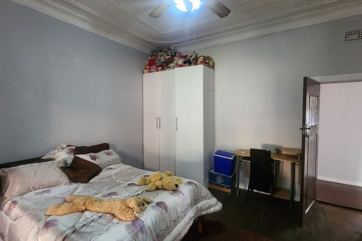 A bedroom featuring a built-in wardrobe, decorative ceiling cornice, and a ceiling fan.
