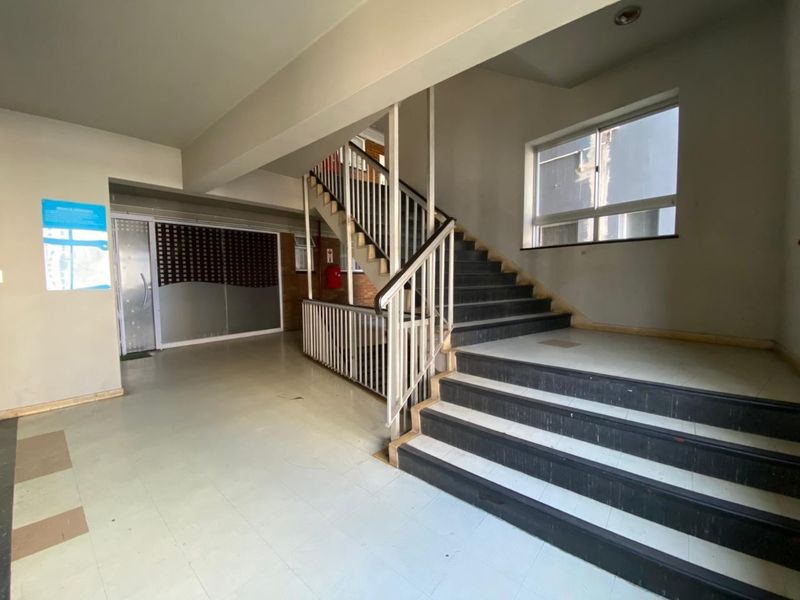 A communal apartment building entrance hall featuring a staircase with metal railings and tiled flooring.