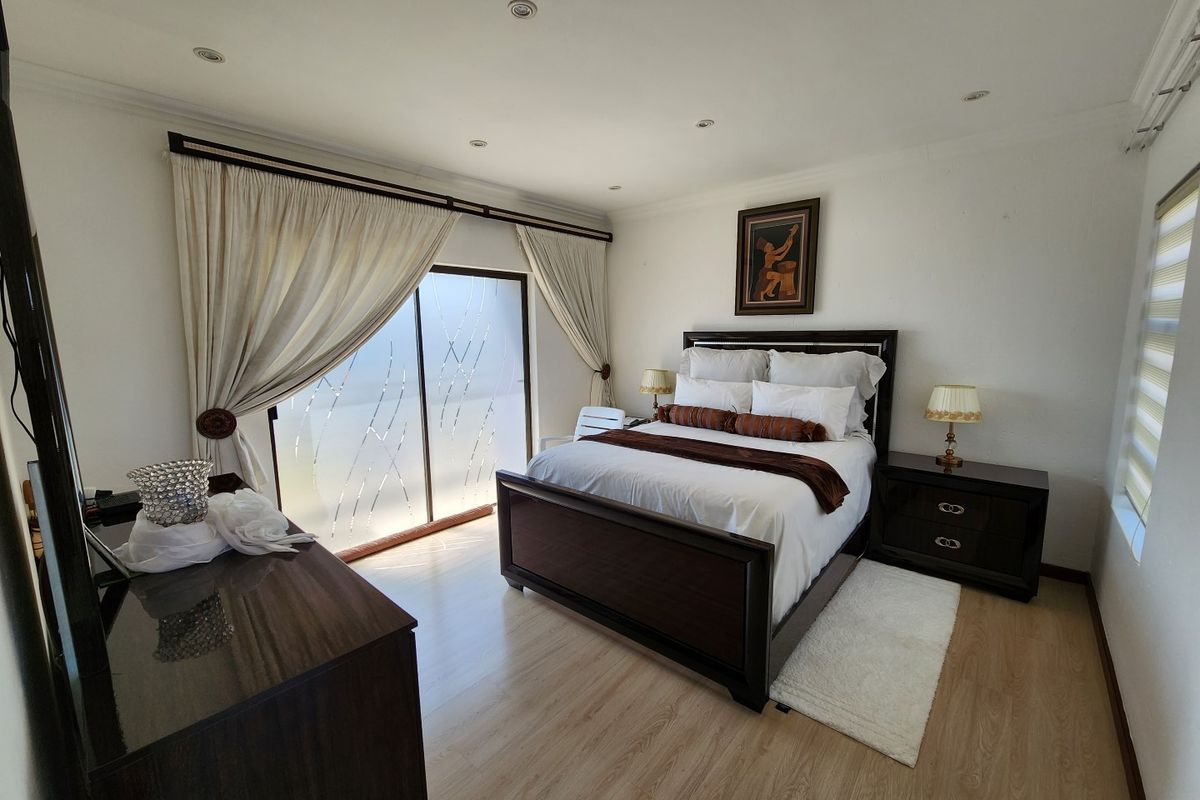 A well-maintained bedroom featuring light wood-look flooring, recessed ceiling lighting, and a sliding glass door with decorative privacy film.