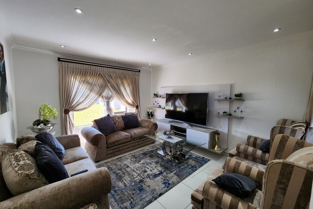 A well-maintained living room featuring recessed ceiling lighting, tiled flooring, and a built-in media wall unit.