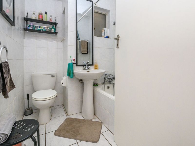 A functional bathroom featuring a pedestal sink, toilet, and bathtub with tiled finishes throughout.
