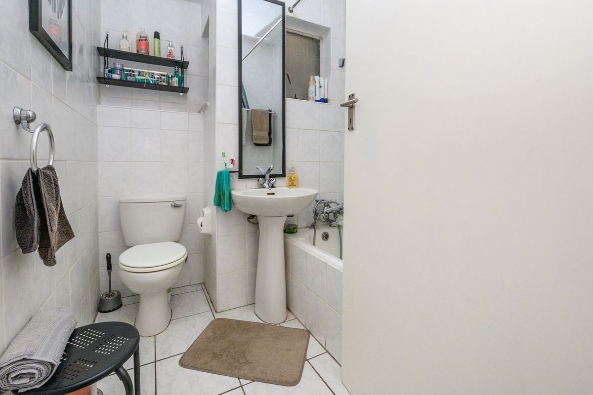 A functional bathroom featuring a pedestal sink, toilet, and bathtub with tiled finishes throughout.