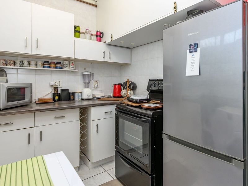 A functional kitchen featuring white cabinetry, laminate countertops, tiled backsplash, and a freestanding oven, providing a practical workspace for daily cooking.