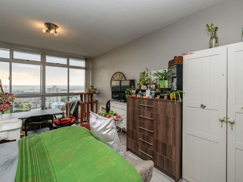 A bedroom featuring large windows with expansive city and ocean views, providing ample natural light and a spacious feel.