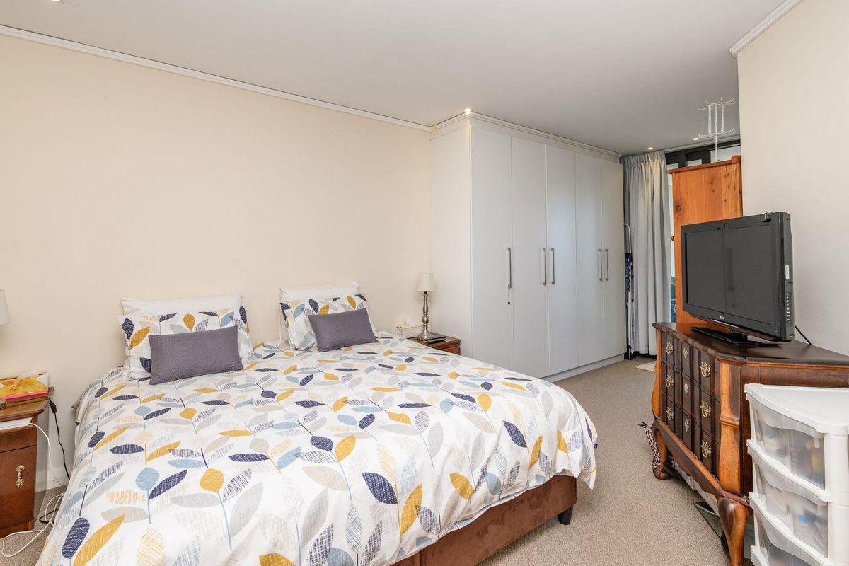 A well-proportioned bedroom featuring neutral walls, carpeted flooring, recessed lighting, and a large built-in wardrobe for ample storage.
