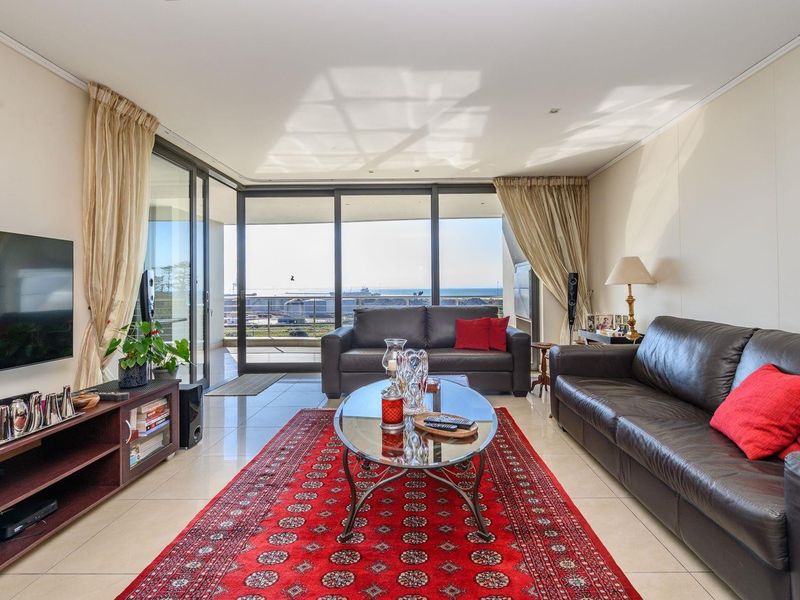 Spacious living room featuring large sliding glass doors that open to a balcony with ocean views and abundant natural light.